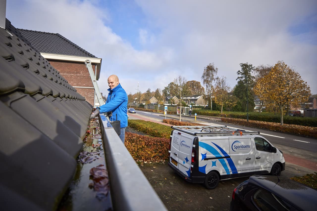 Medewerker van Sparidaens maakt een dakgoot schoon in Hulsel